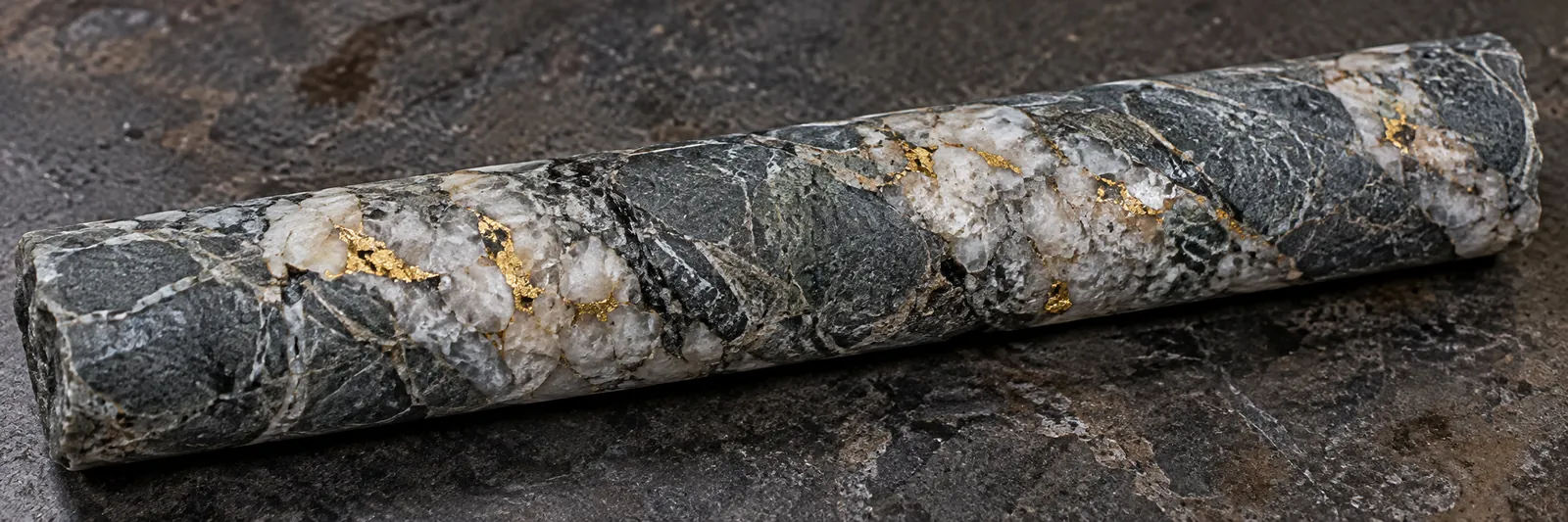 Illustrative diamond drill core with small gold flecks in quartz veins